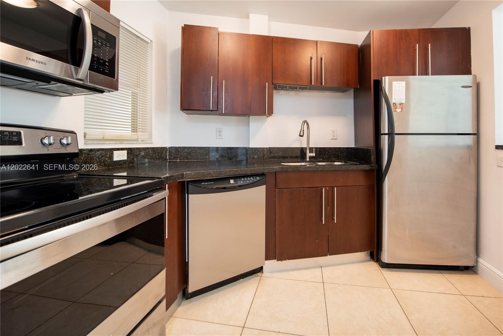 A kitchen features dark wood cabinets, stainless steel appliances, and dark granite countertops — 4147 Stirling Rd # 105, Dania Beach FL 33314, DANIA BEACH, FL