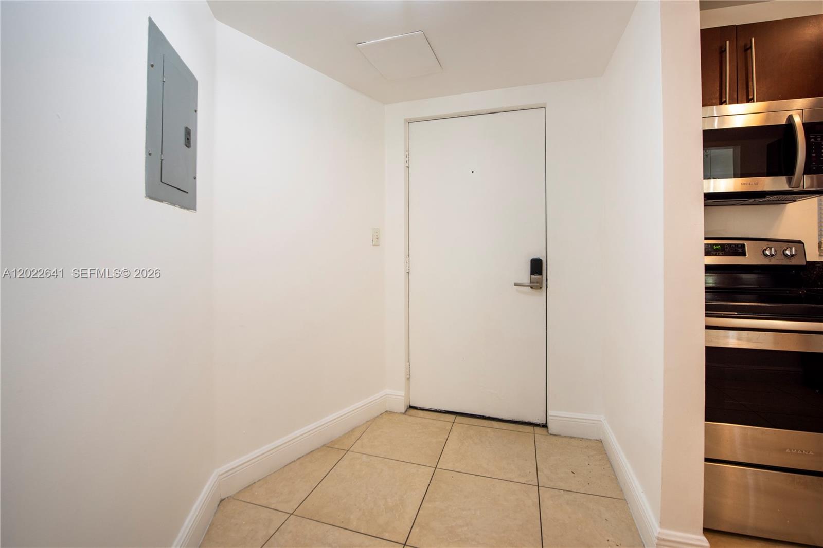 A white entry door is positioned next to a kitchen with stainless steel appliances — 4147 Stirling Rd # 105, Dania Beach FL 33314, DANIA BEACH, FL