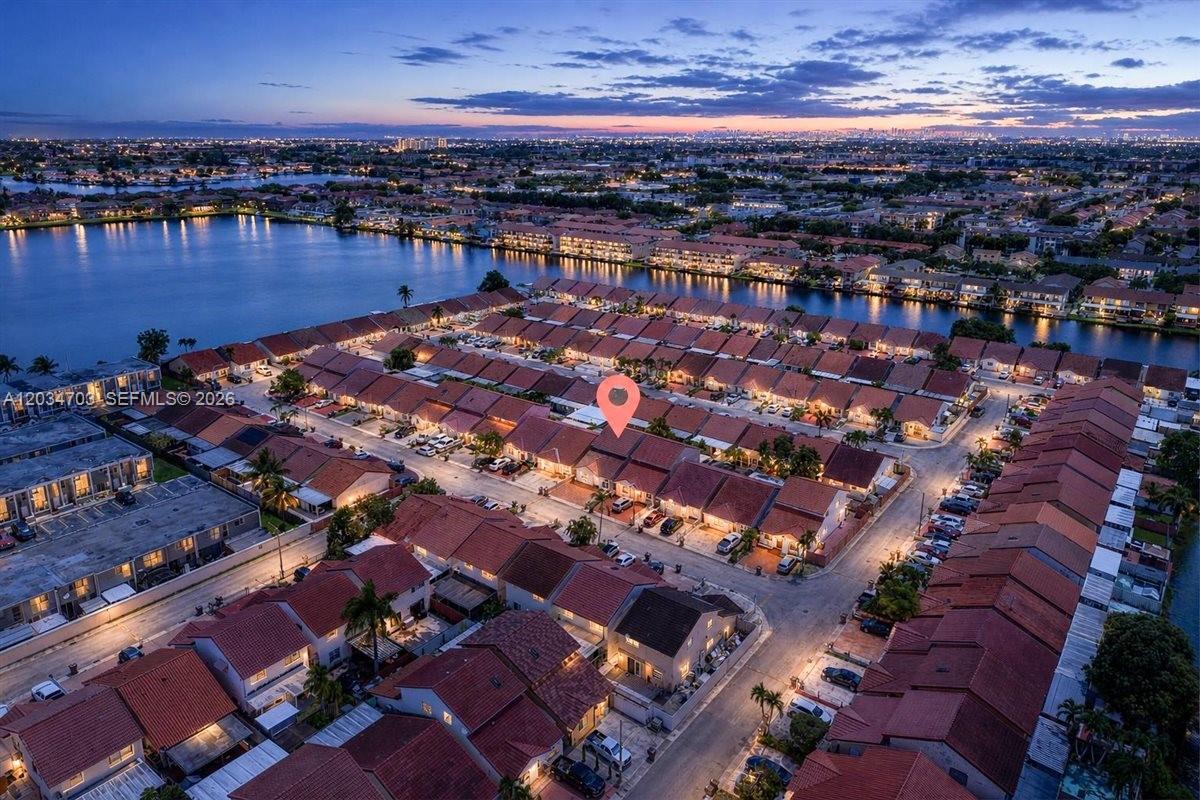 An aerial view shows a residential neighborhood of townhomes with red roofs near a lake — 5445 W 27th Lane, Hialeah FL 33016, HIALEAH, FL