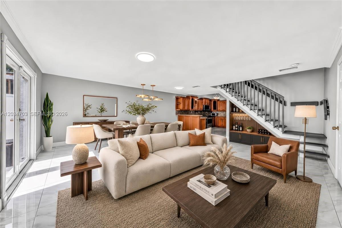 An open-concept living and dining area features a staircase, tile flooring, and wood cabinetry — 5445 W 27th Lane, Hialeah FL 33016, HIALEAH, FL