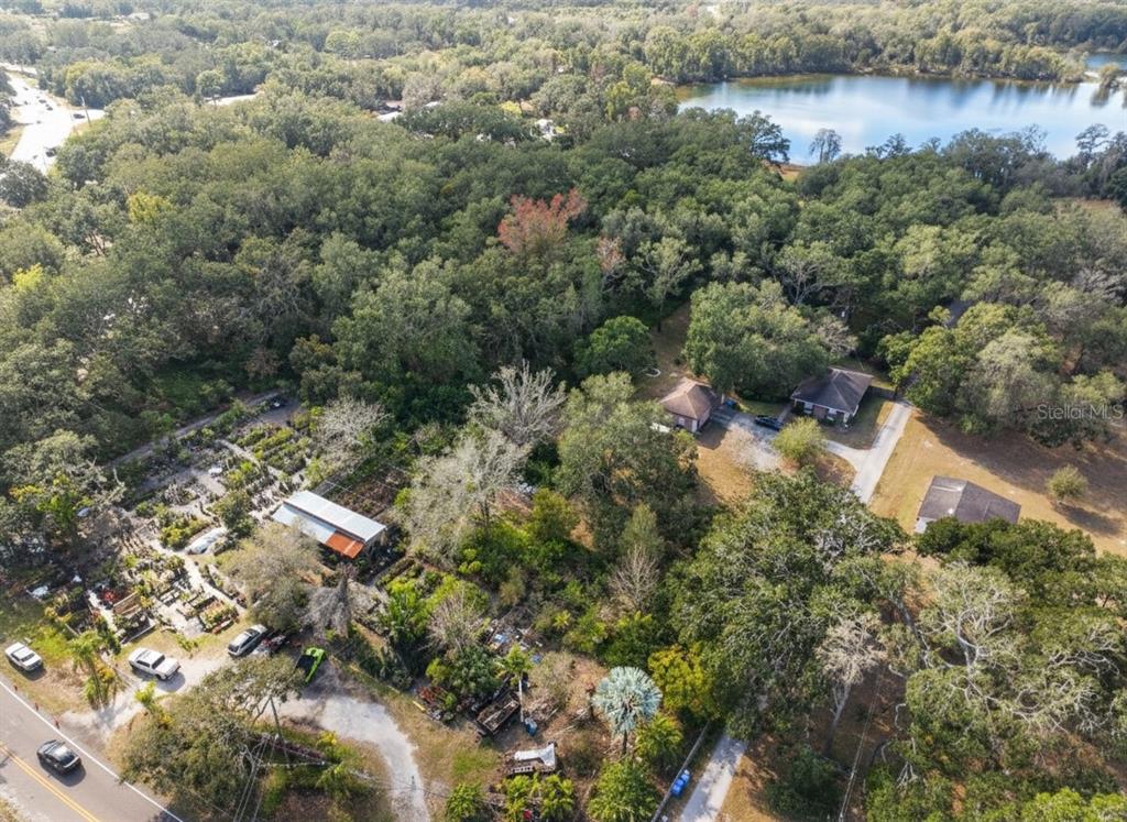 An aerial view shows a property with a nursery, several houses, and a nearby lake — 0000 GUNN HIGHWAY, ODESSA, FL