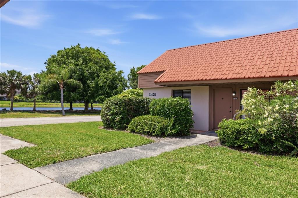 A one-story building with a red tile roof and a concrete walkway leading to the entrance — 6628 DRAW LANE UNIT 122, SARASOTA, FL