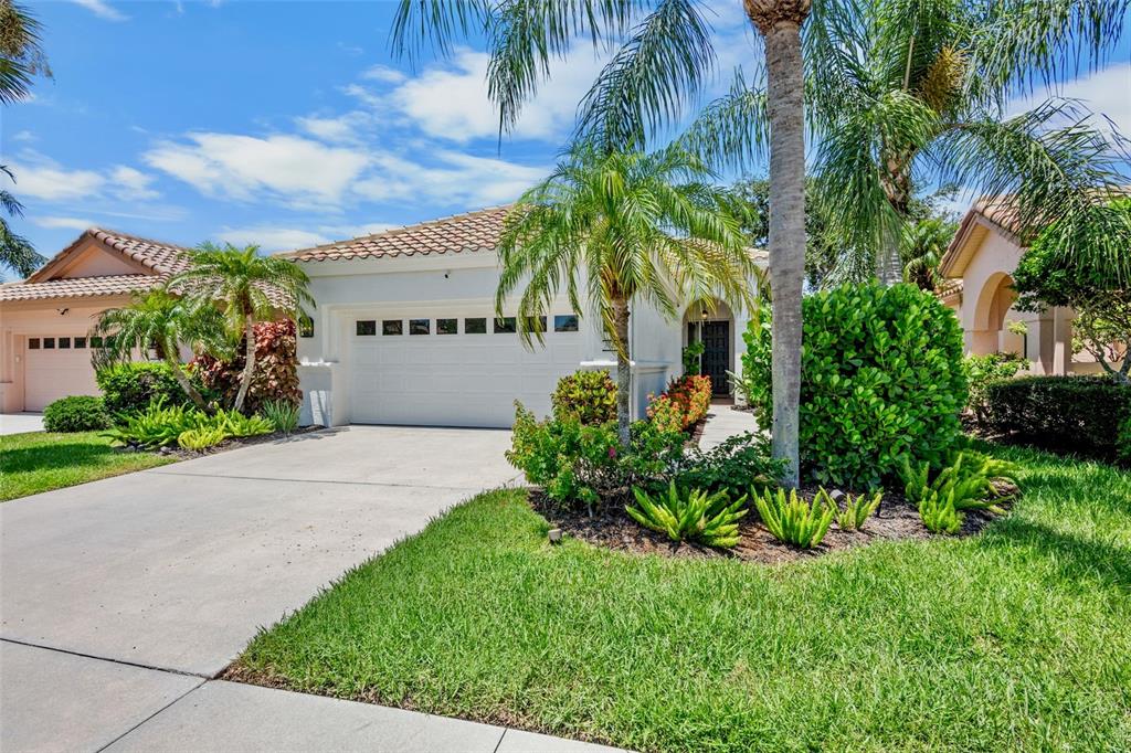 A single-story house with a white garage, tiled roof, and palm trees in the front yard — 3761 AMAPOLA LANE, SARASOTA, FL