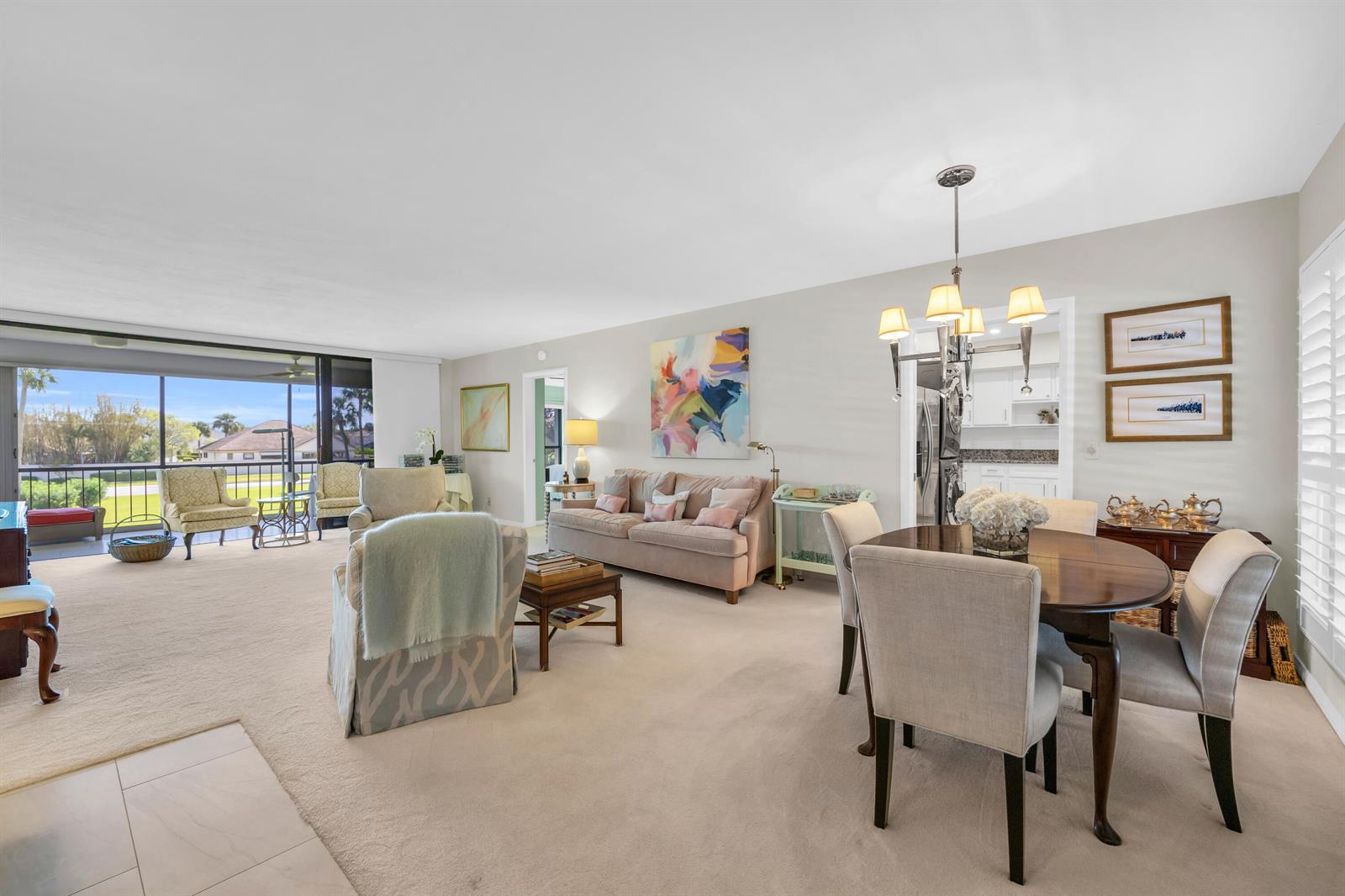 A living and dining area with beige carpet, neutral furniture, and a sliding glass balcony door — 4 SE Turtle Creek Drive, Jupiter FL 33469, JUPITER, FL