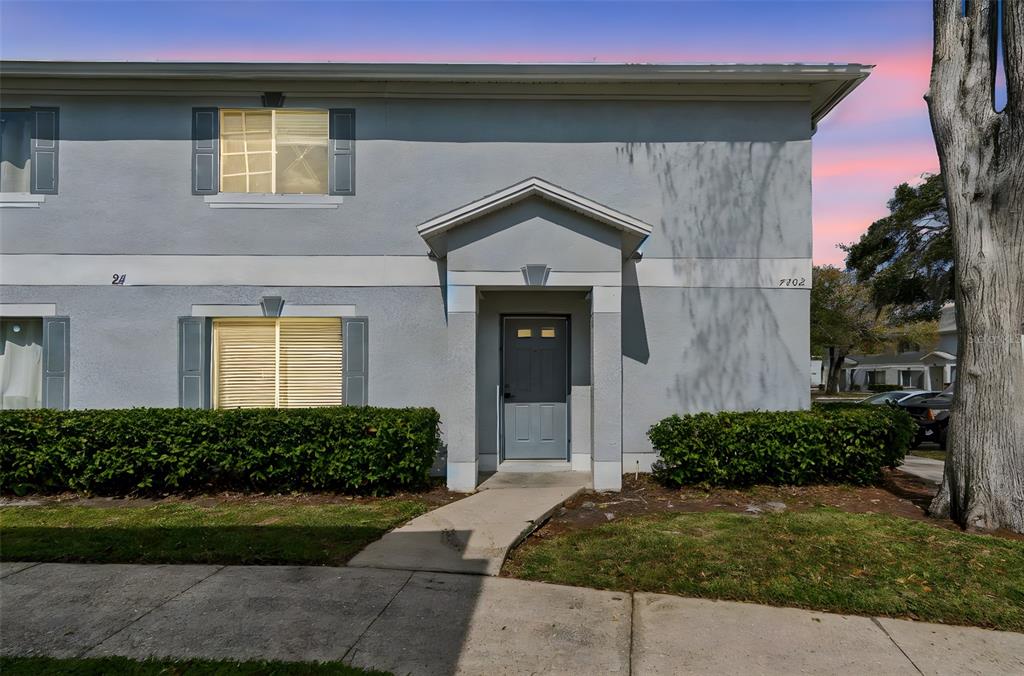 A two-story gray stucco building features a central front entrance and two ground-floor windows — 7402 E BANK DRIVE, TAMPA, FL