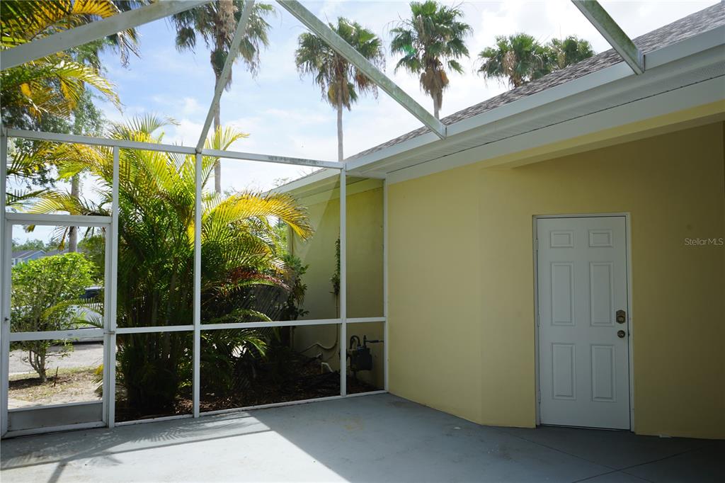 A screened-in patio with a concrete floor and a white door against a yellow wall — 201 SUNSET CREST COURT, APOLLO BEACH, FL