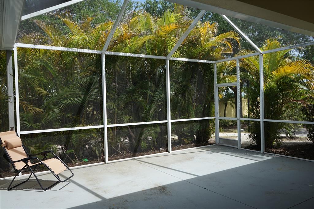 A screened-in patio with a concrete floor, a lounge chair, and views of palm trees — 201 SUNSET CREST COURT, APOLLO BEACH, FL