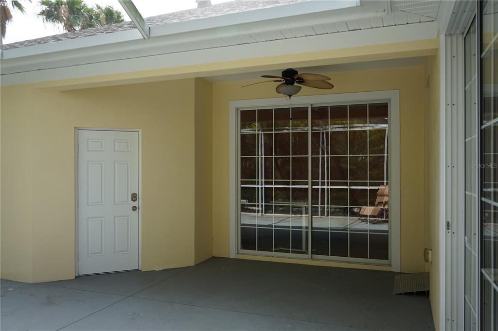 A covered patio features yellow walls, a ceiling fan, a white door, and sliding glass doors — 201 SUNSET CREST COURT, APOLLO BEACH, FL