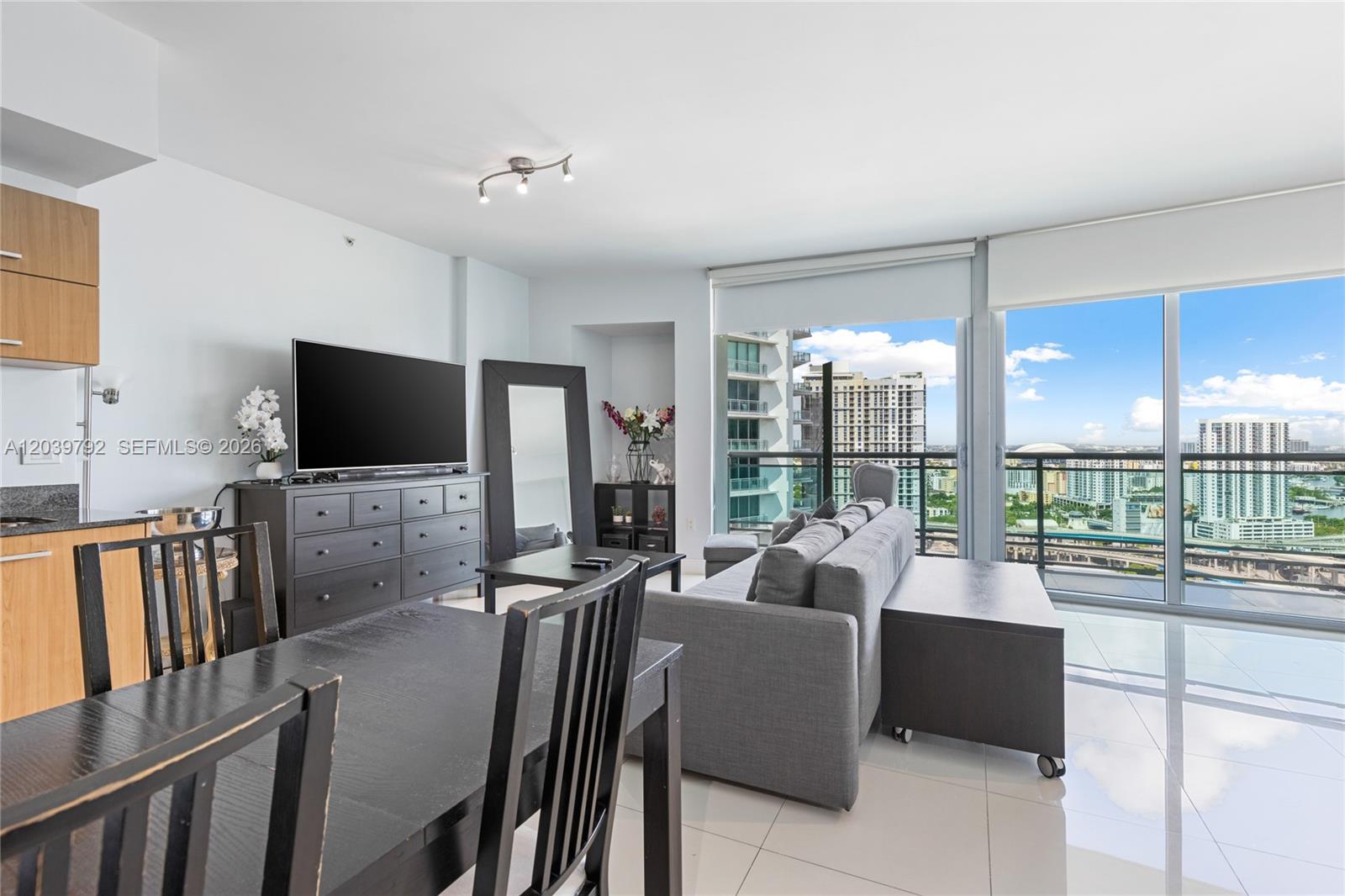 A modern living room features a gray sofa, dining set, and floor-to-ceiling windows — 350 S Miami Ave # 2815, Miami FL 33130, MIAMI, FL