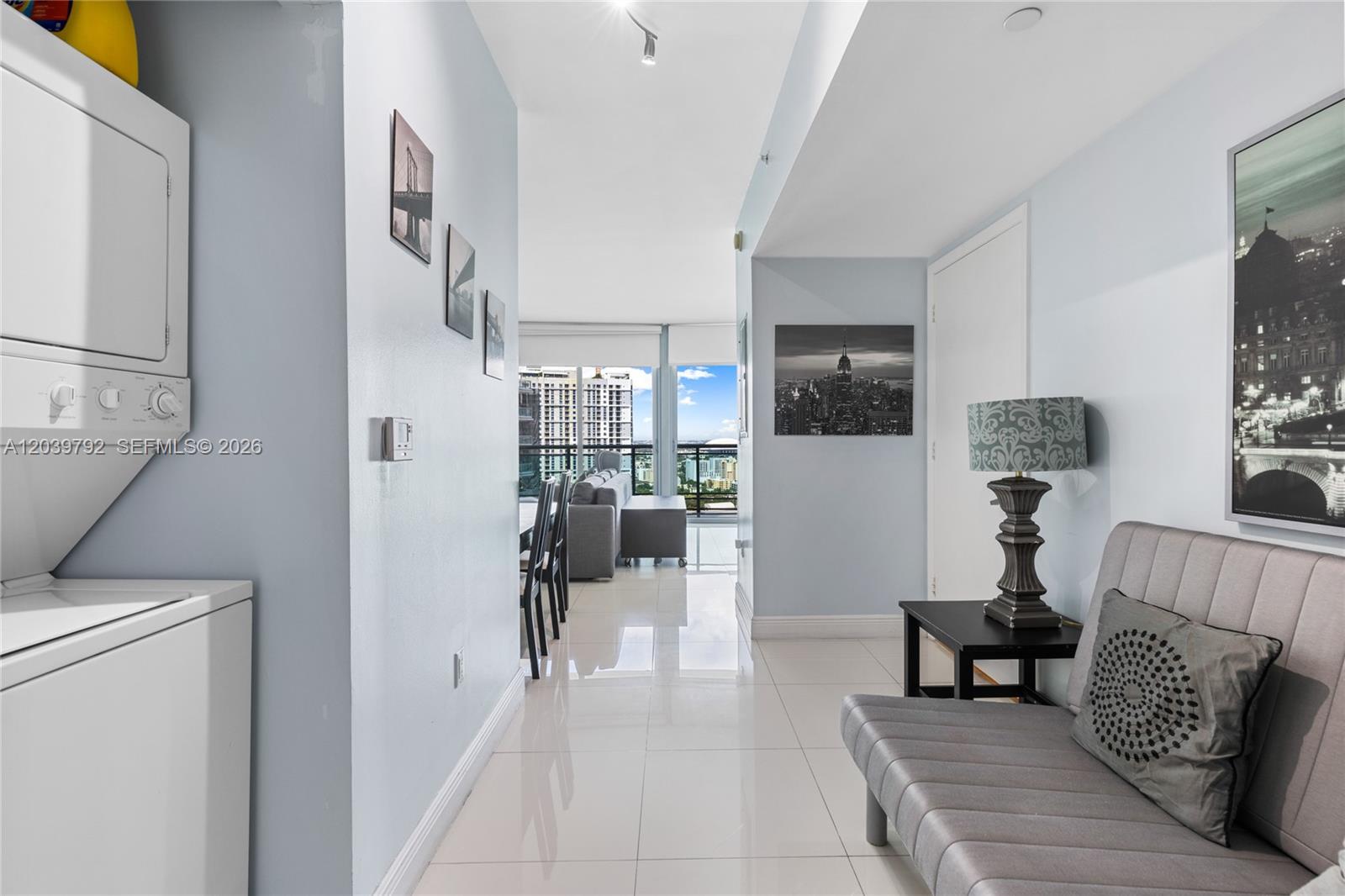 A hallway with light blue walls, tile flooring, a laundry unit, and a seating area — 350 S Miami Ave # 2815, Miami FL 33130, MIAMI, FL