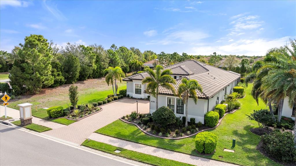 An aerial view shows a single-story house with a tiled roof and a paved driveway — 16316 CASTLE PARK TERRACE, LAKEWOOD RANCH, FL
