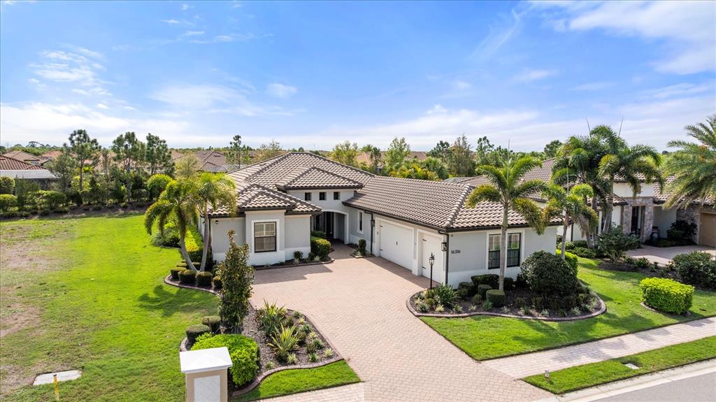 An aerial view shows a single-story house with a tiled roof and a paved driveway — 16316 CASTLE PARK TERRACE, LAKEWOOD RANCH, FL