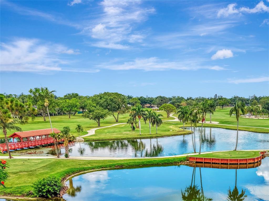 A golf course view features a red wooden bridge over a pond with palm trees — 5030 18TH AVENUE W, BRADENTON, FL