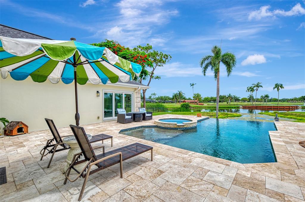 A patio features a swimming pool, hot tub, lounge chairs, and a colorful umbrella — 5030 18TH AVENUE W, BRADENTON, FL