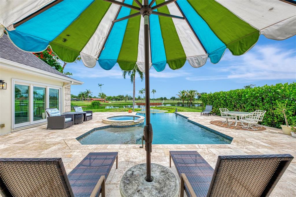 A patio features a swimming pool, a hot tub, lounge chairs, and a striped umbrella — 5030 18TH AVENUE W, BRADENTON, FL