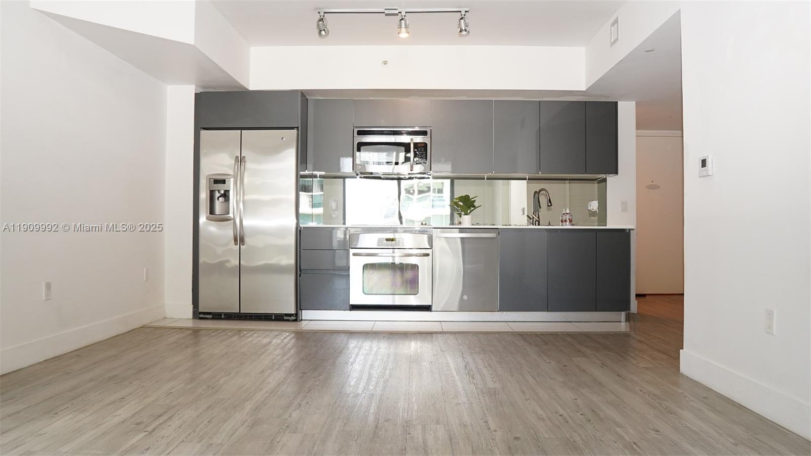 A kitchen features gray cabinetry, stainless steel appliances, and light wood-look flooring — 31 SE 6th St # 1108, Miami FL 33131, MIAMI, FL