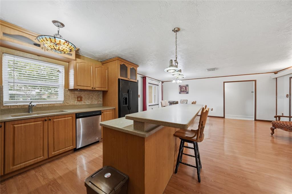 A kitchen with wood cabinets, a breakfast bar, and stainless steel appliances opens to a room — 3250 SANTA BARBARA DRIVE, PUNTA GORDA, FL
