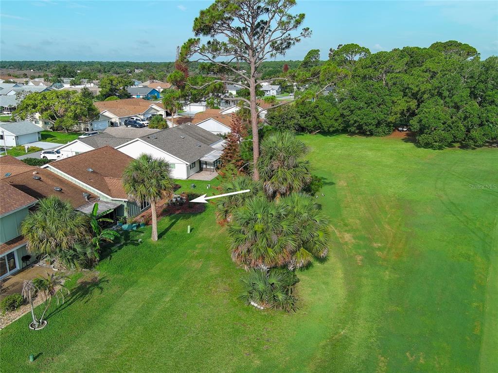 An aerial view shows a residential house with a yard bordering a large grassy field — 25 ANDREA DRIVE, NEW SMYRNA BEACH, FL