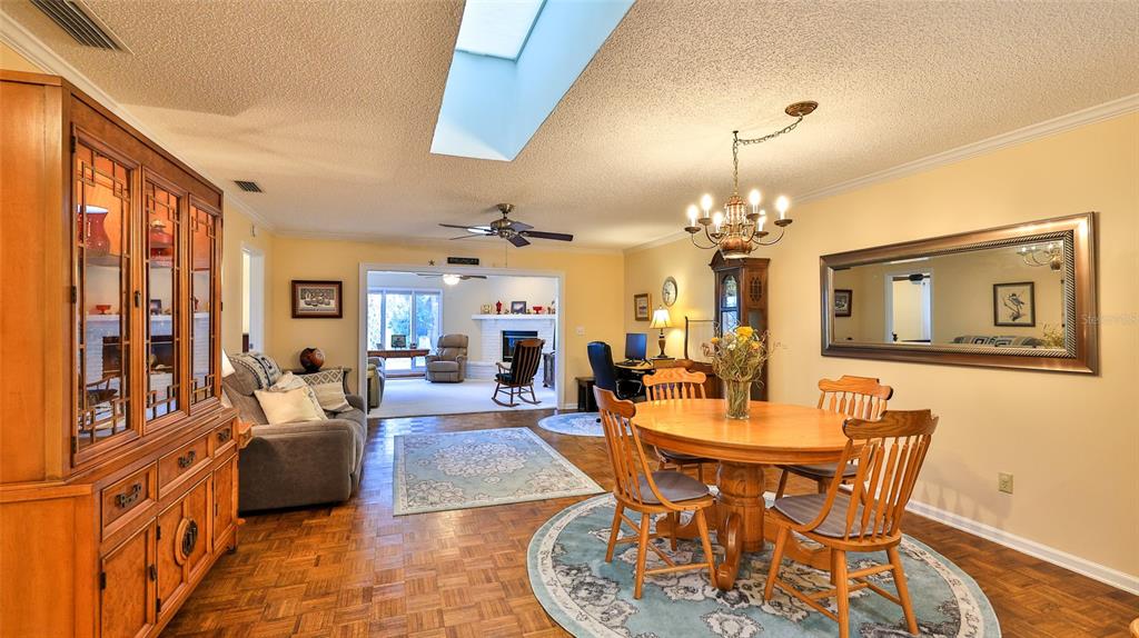 A dining area with a round wooden table and chairs sits beside a living room — 25 ANDREA DRIVE, NEW SMYRNA BEACH, FL