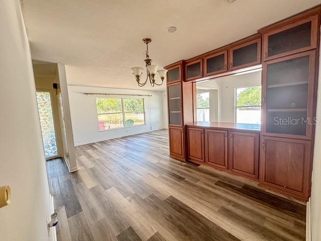 A dining room features wood-look flooring, a chandelier, and a large built-in wooden cabinet — 121 E PINE ST, HOWEY IN THE HILLS, FL
