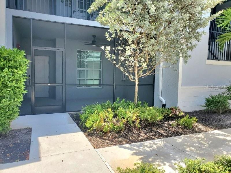 A ground-level patio with a screen enclosure and a ceiling fan sits beside a tree — 14194 HERITAGE LANDING BOULEVARD UNIT 611, PUNTA GORDA, FL