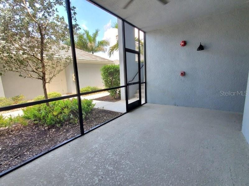 A screened-in patio with a concrete floor, a door, and a view of landscaping — 14194 HERITAGE LANDING BOULEVARD UNIT 611, PUNTA GORDA, FL