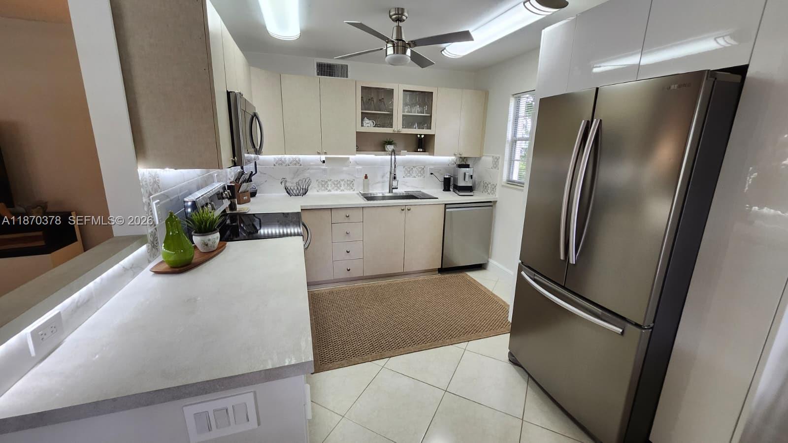 A kitchen features light-colored cabinets, stainless steel appliances, a ceiling fan, and tile flooring — 2001 Ventnor G # 2001, Deerfield Beach FL 33442, DEERFIELD BEACH, FL