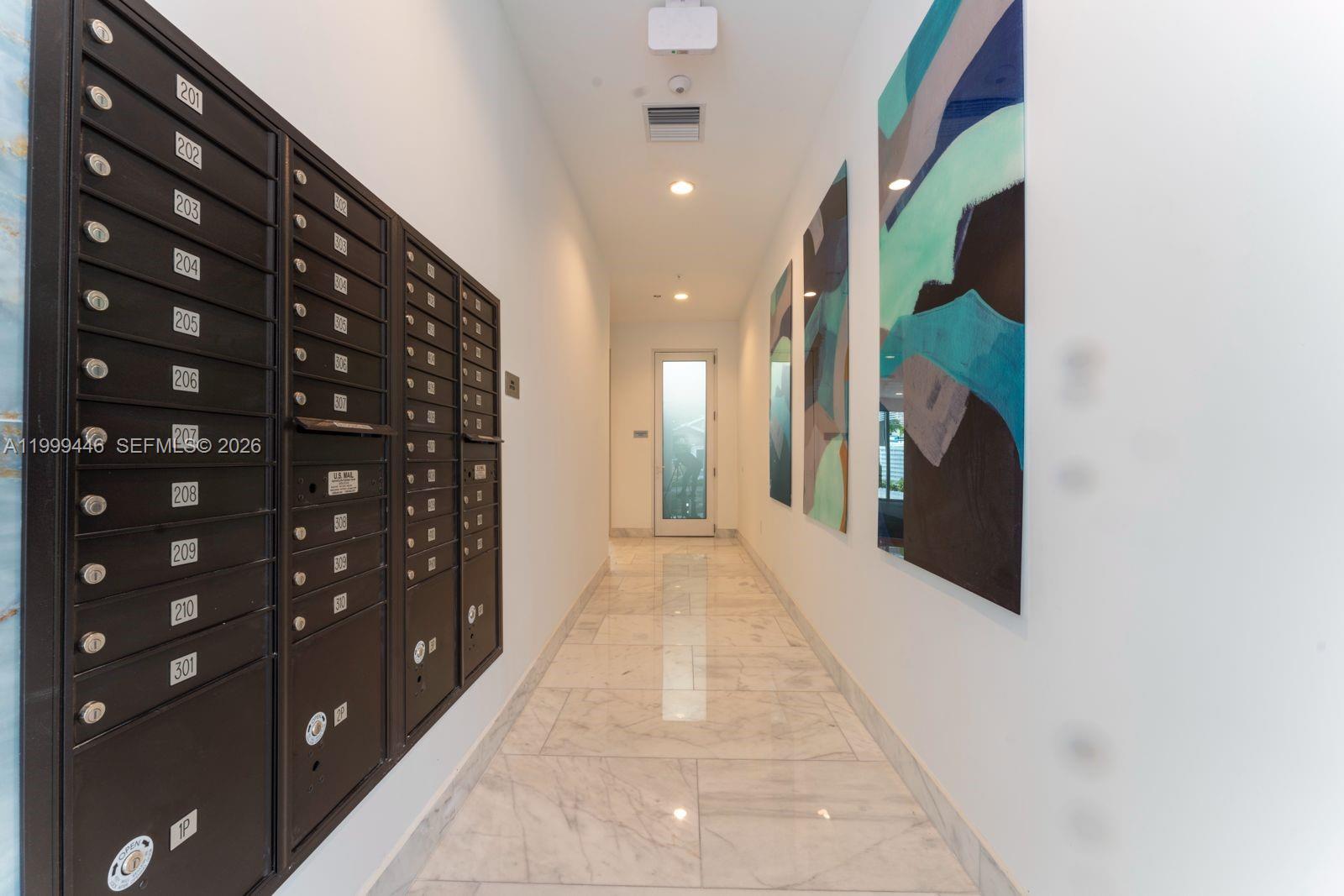 A hallway features marble floors, wall-mounted mailboxes, and abstract art on the walls — 1850 Monroe St # 403, Hollywood FL 33020, HOLLYWOOD, FL
