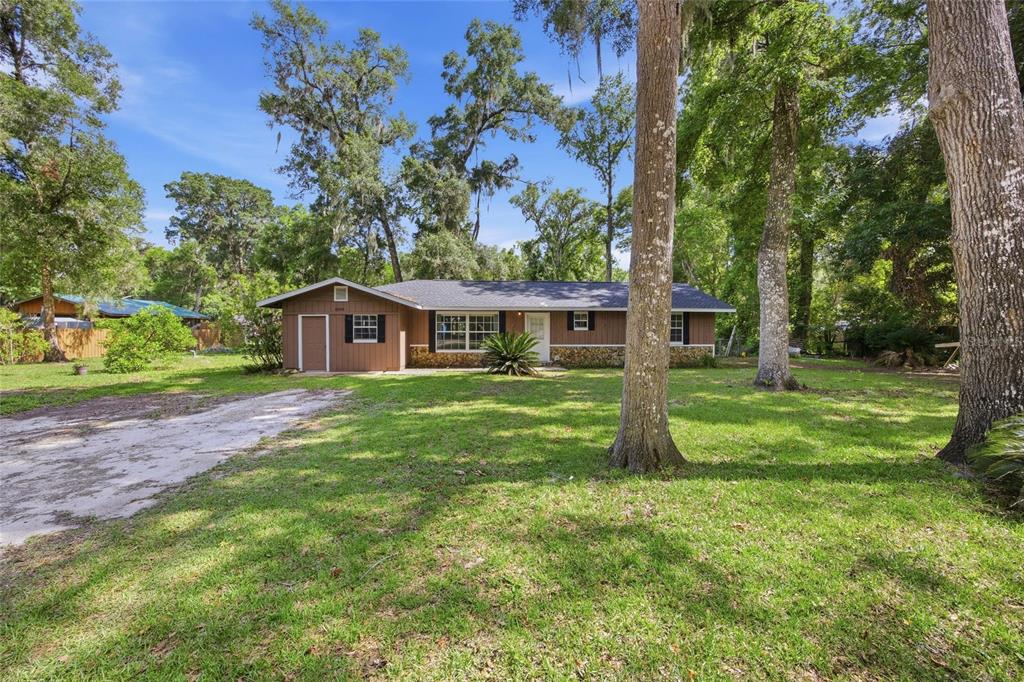 A single-story house with brown siding and a stone base sits on a grassy lot — 4300 NE 132ND PLACE, ANTHONY, FL