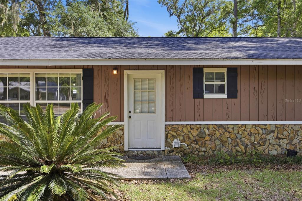 The exterior of a house features brown vertical siding, a stone base, and a white door — 4300 NE 132ND PLACE, ANTHONY, FL