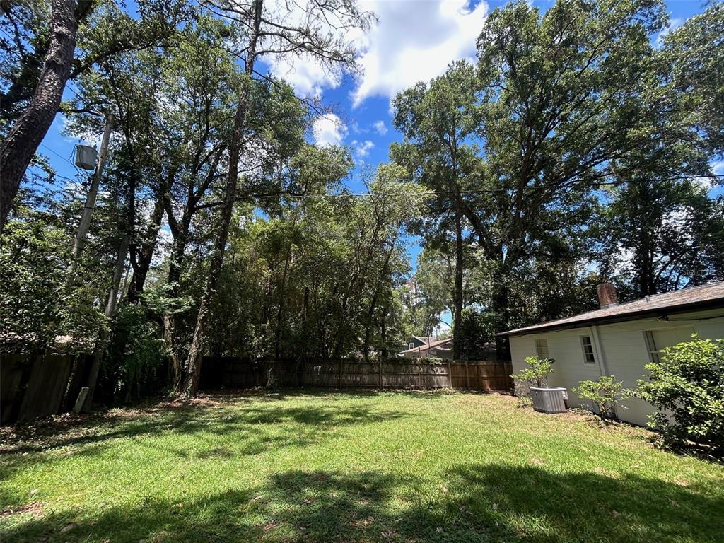 A covered carport features a concrete floor, white vertical siding, and a side entry door — 3035 W UNIVERSITY AVENUE, GAINESVILLE, FL