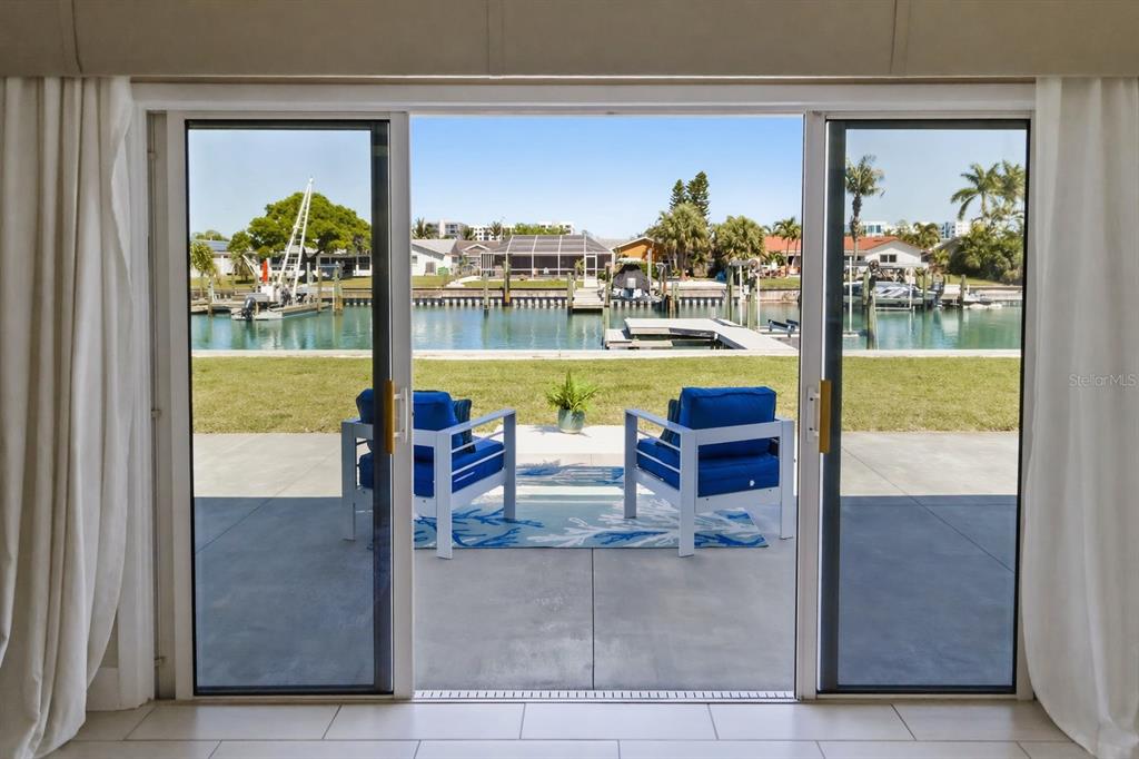 A view through sliding glass doors shows a patio with two blue chairs overlooking a canal — 4462 39TH STREET S, ST PETERSBURG, FL