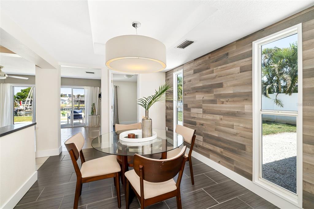 A dining area features a glass table, wood-plank accent wall, and tile flooring — 4462 39TH STREET S, ST PETERSBURG, FL