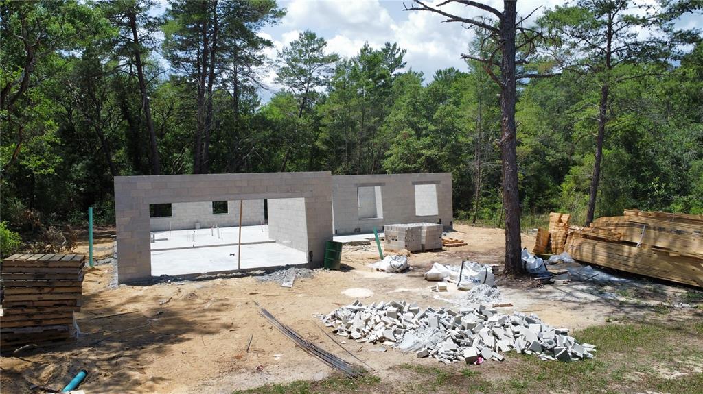 A construction site shows concrete block walls and a concrete slab foundation amid a wooded area — 2612 SHEPHARD STREET, INVERNESS, FL