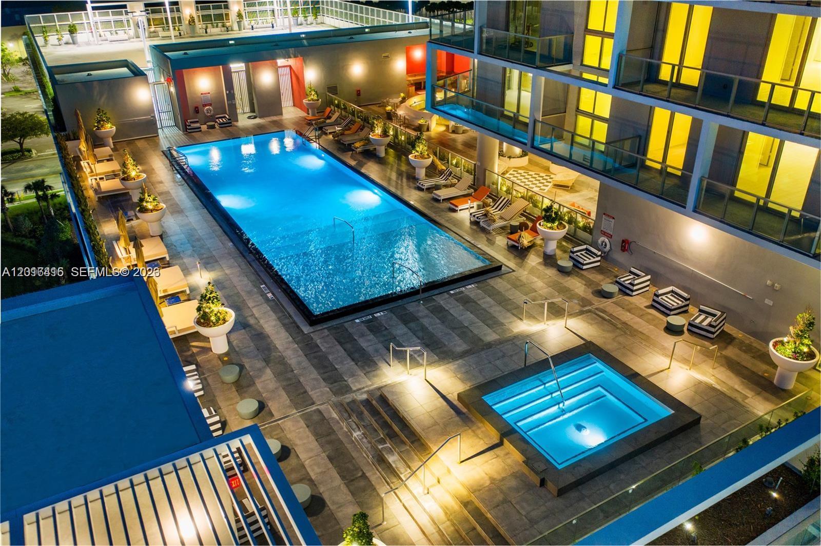 An elevated view of a lit swimming pool and hot tub on a building terrace — 2000 Metropica Way # 2006, Sunrise FL 33323, SUNRISE, FL