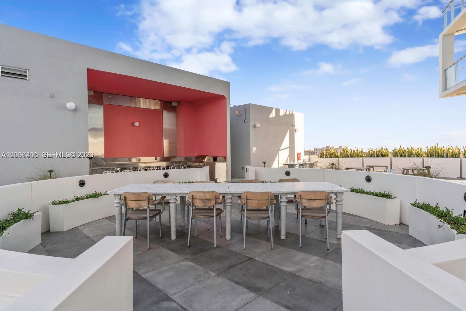 An outdoor rooftop terrace features a long dining table, seating, and a built-in grill area — 2000 Metropica Way # 2006, Sunrise FL 33323, SUNRISE, FL