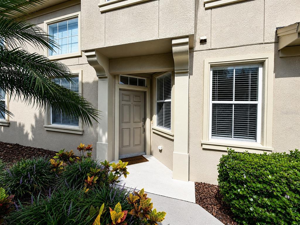 The exterior of a tan two-story building features a front door, windows, and landscaping — 6648 83RD AVENUE N, PINELLAS PARK, FL