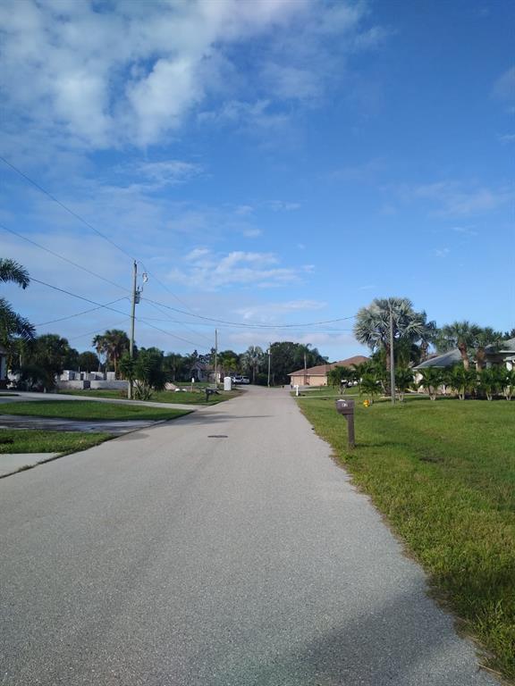A paved residential street lined with palm trees and houses under a blue sky — 81 LONG MEADOW PLACE, ROTONDA WEST, FL
