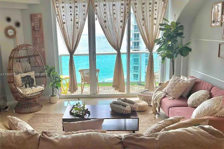 A living room features a wicker egg chair, pink sofa, and floor-to-ceiling ocean views — 3901 S Ocean Dr # 14L, Hollywood FL 33019, HOLLYWOOD, FL