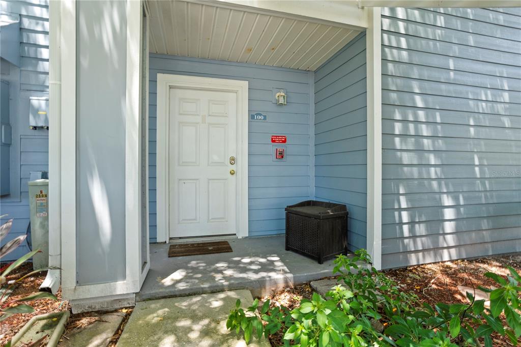 The exterior entrance of a residential building features a white door, blue siding, and porch — 2504 GRASSY POINT DRIVE UNIT 100, LAKE MARY, FL