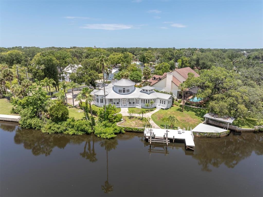 An aerial view shows a waterfront house with a central rotunda and a private dock — 5617 PALMETTO ROAD, NEW PORT RICHEY, FL