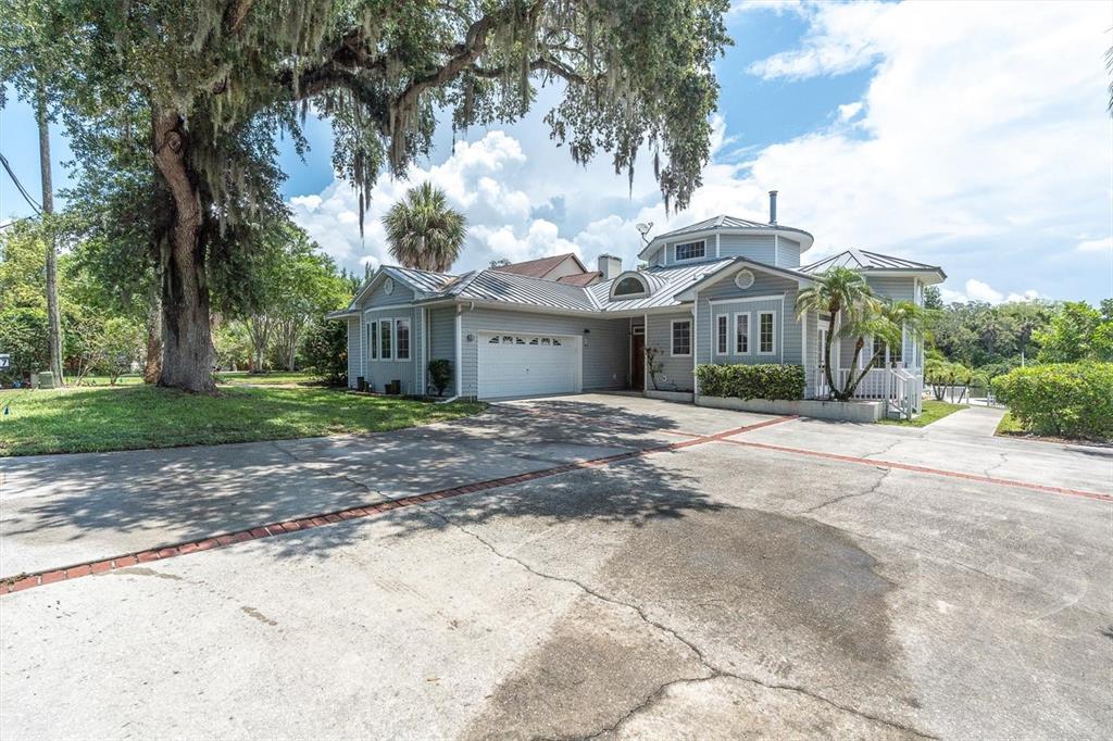 A light blue house with a metal roof and a large concrete driveway — 5617 PALMETTO ROAD, NEW PORT RICHEY, FL
