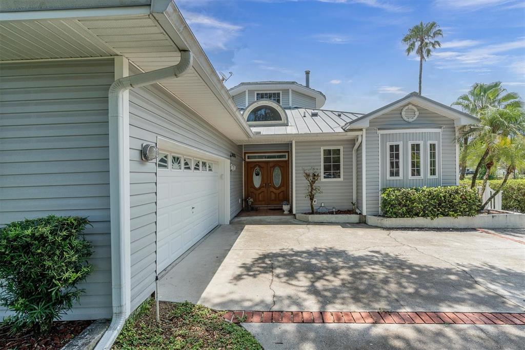 A light blue house with a metal roof, a garage, and a concrete driveway — 5617 PALMETTO ROAD, NEW PORT RICHEY, FL