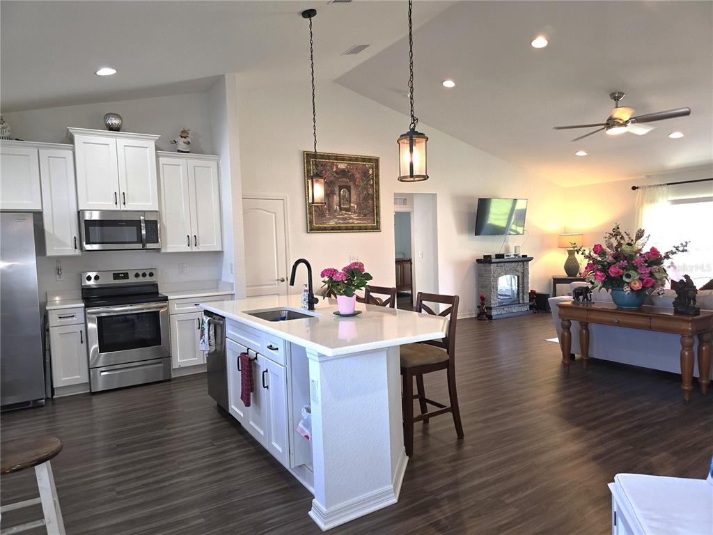 A kitchen with white cabinets and a center island opens into a living area — 4823 SAN IGNACIO DRIVE, SEBRING, FL