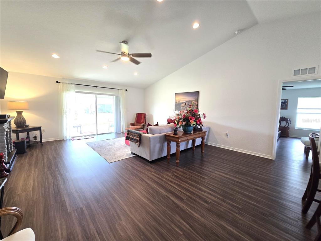 A living room features wood-look flooring, a vaulted ceiling, and a sliding glass door — 4823 SAN IGNACIO DRIVE, SEBRING, FL