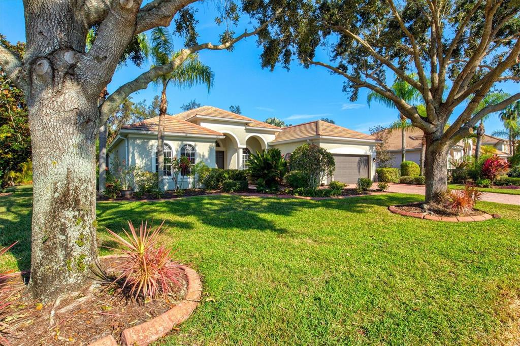 A single-story house with a tiled roof and a large front lawn with trees — 14757 2ND AVENUE CIRCLE NE, BRADENTON, FL