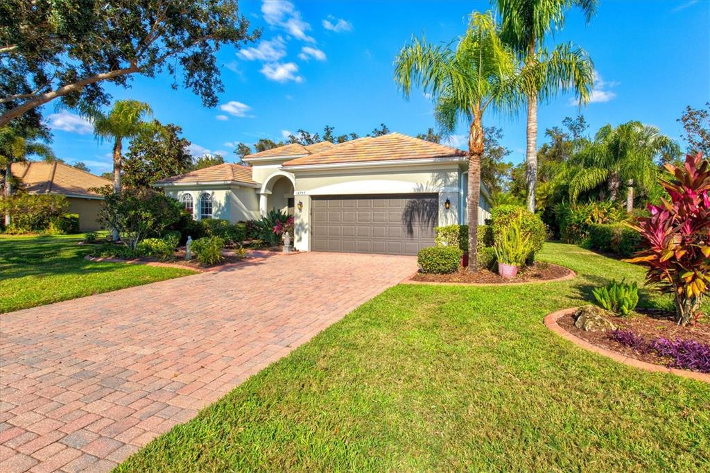 A single-story house with a brick paver driveway, a two-car garage, and tropical landscaping — 14757 2ND AVENUE CIRCLE NE, BRADENTON, FL