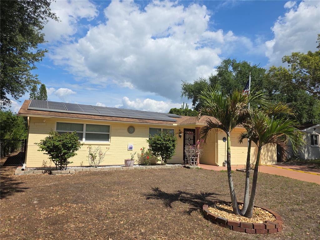 A yellow, single-story house with solar panels on the roof and a palm tree out front — 4832 ELMWOOD STREET, NEW PORT RICHEY, FL