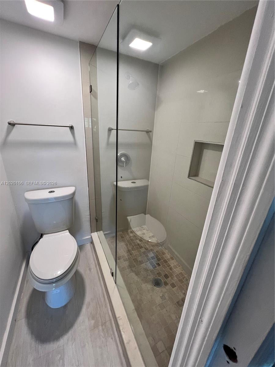 A bathroom features a toilet next to a glass-enclosed shower with tiled walls and flooring — 3621 NW 95th Ter # 523, Sunrise FL 33351, SUNRISE, FL