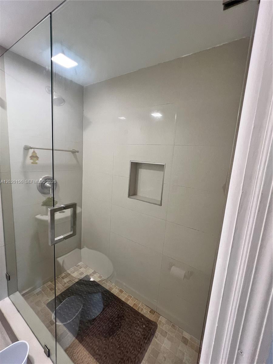 A glass-enclosed shower features light-colored wall tiles, a recessed niche, and a tiled floor — 3621 NW 95th Ter # 523, Sunrise FL 33351, SUNRISE, FL